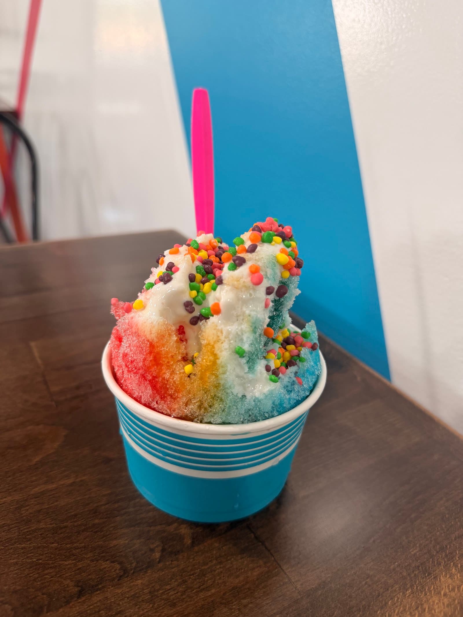 A rainbow snowball topped with sprinkles in a Just Chillin' cup